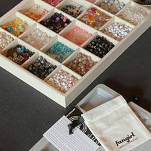 Load image into Gallery viewer, Box of assorted beads with a fangirl branded pouch and card on a dark surface