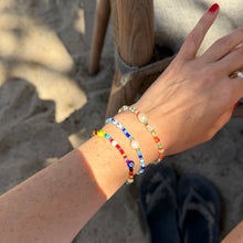 Load image into Gallery viewer, Colorful beaded bracelet on a wrist with a sandy background