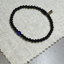 Load image into Gallery viewer, Overhead shot of black onyx bead bracelet with glass evil eye bead