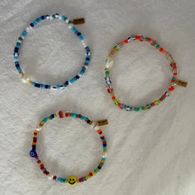 Load image into Gallery viewer, Three colorful beaded bracelets on a white fabric background
