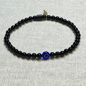 Angled shot of black onyx bead bracelet with glass evil eye bead