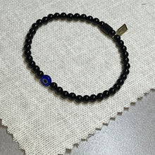 Load image into Gallery viewer, Overhead shot of black onyx bead bracelet with glass evil eye bead
