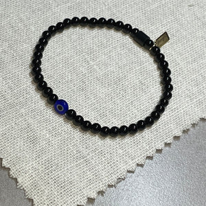 Overhead shot of black onyx bead bracelet with glass evil eye bead