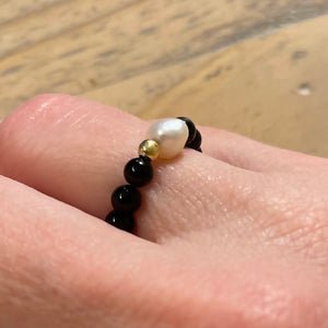 On finger shot of black onyx stretch ring with freshwater pearl and 24k gold vermeil bead